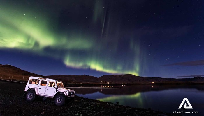 land rover jeep near northern lights in iceland