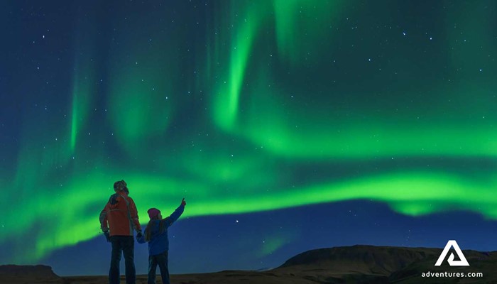 father and son watching northern lights in iceland