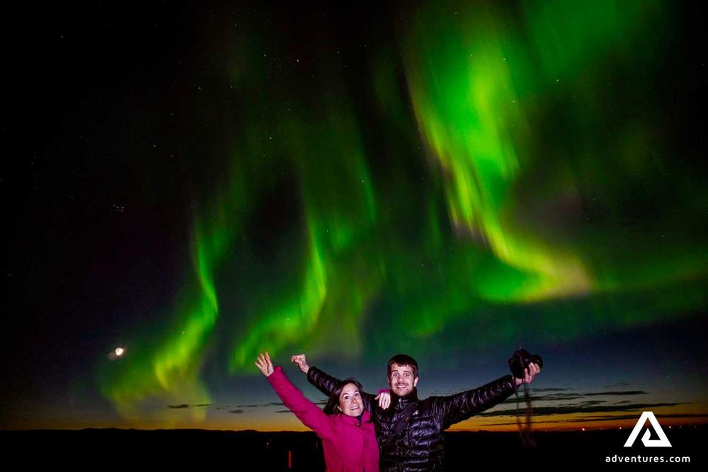 happy couple watching aurora borealis