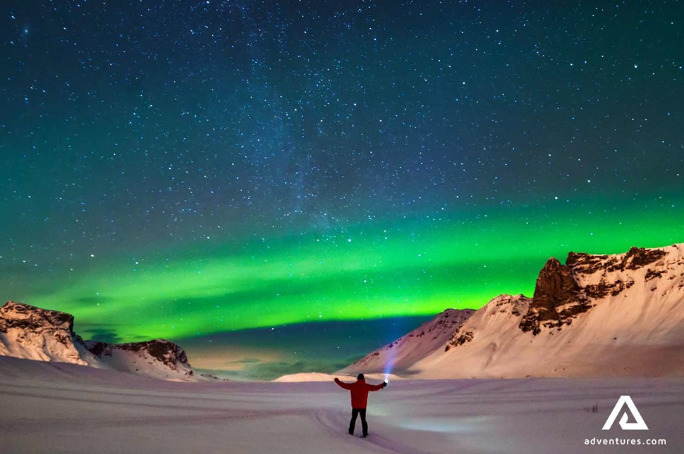 man with a flashlight watching northern lights in winter