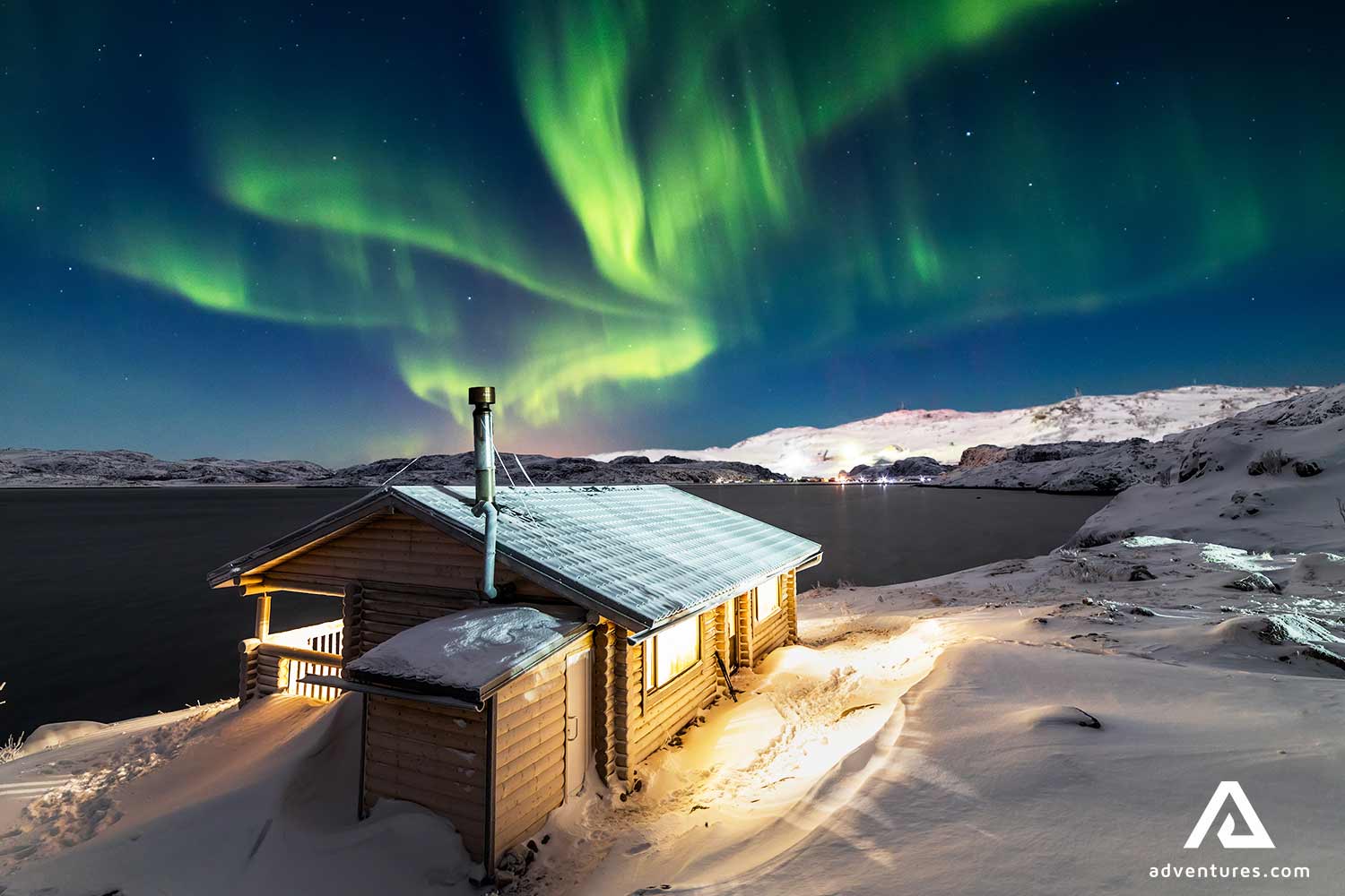 wooden cabin in winter near northern lights