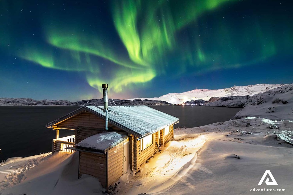 wooden cabin in winter near northern lights in iceland