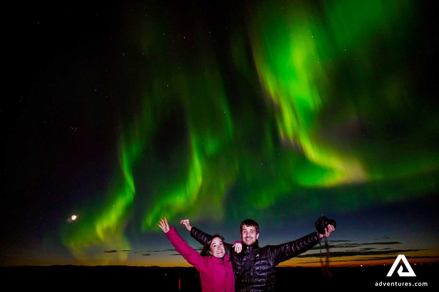 couple spreading arms while watching aurora