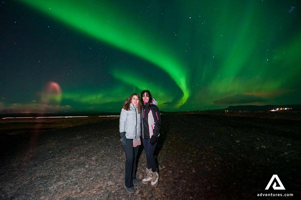 two women posing for a picture near northern lights