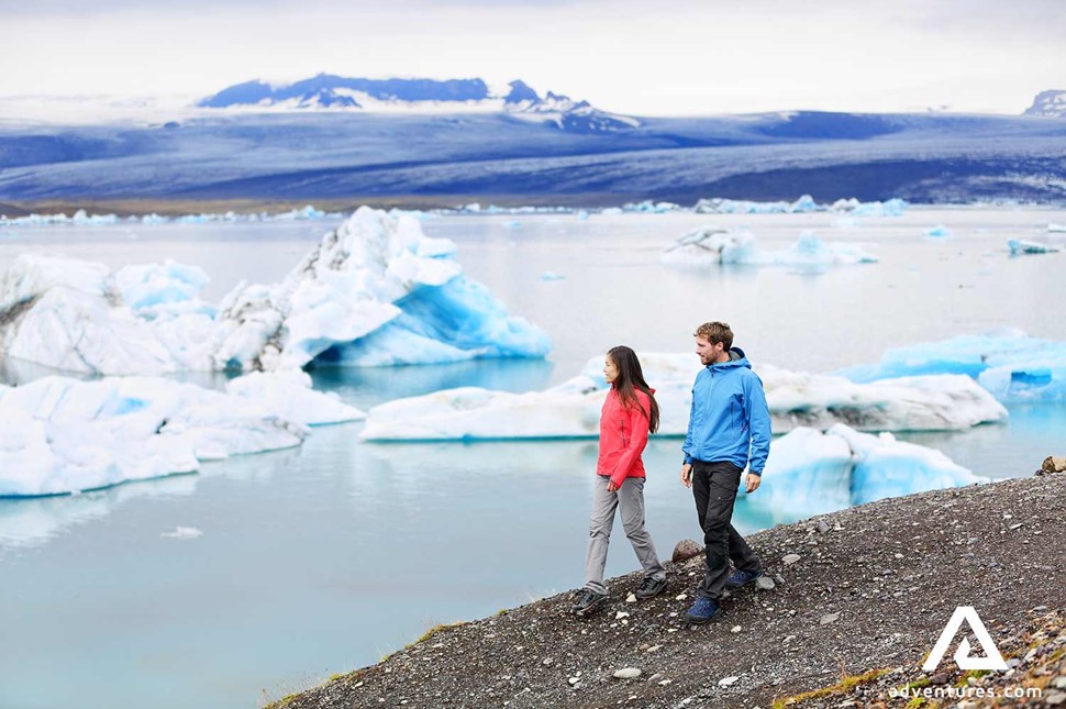 couple walking in jokulsarlon glacier lagoon
