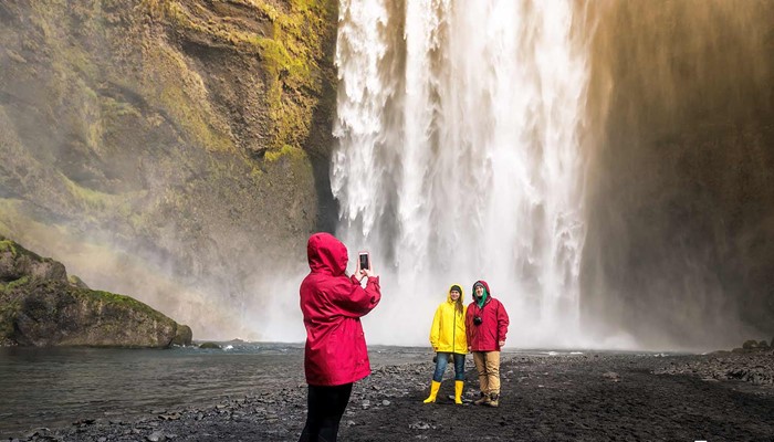 happy people taking pictures near skogafoss in south iceland