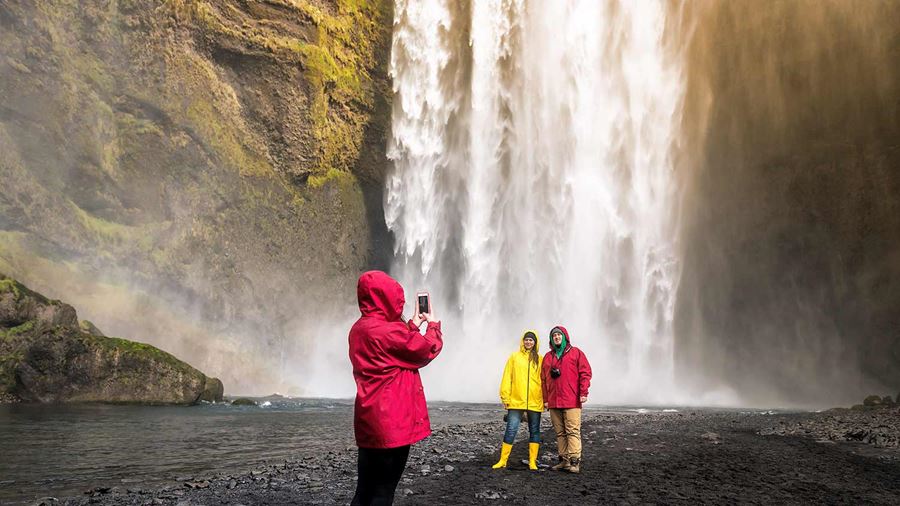 happy people taking pictures near skogafoss