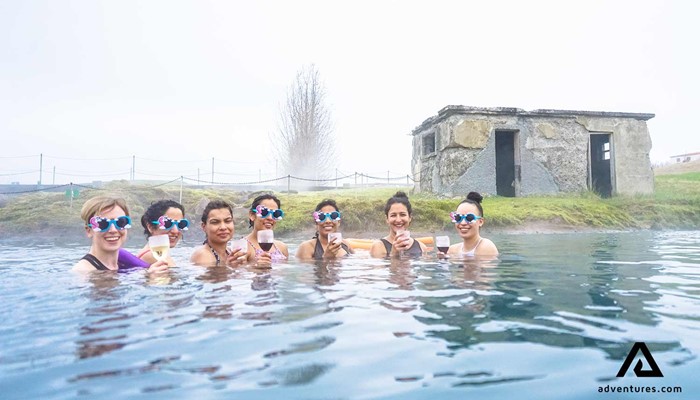 happy women bathing in secret lagoon in iceland