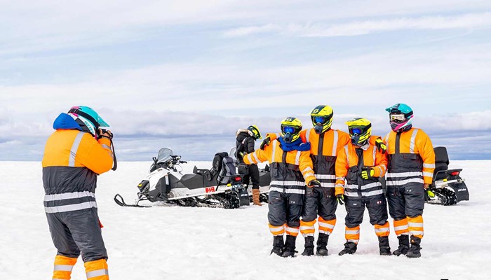 taking pictures of a group near snowmobiles on langjokull
