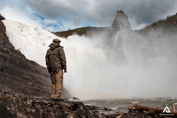 man standing near a powerful waterfall in canada