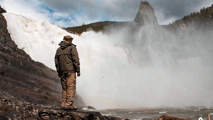 man standing near a powerful waterfall