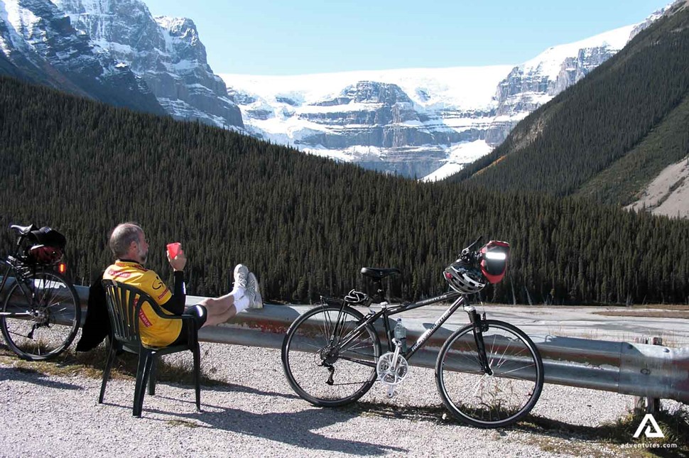 cyclist relaxing on a bench near mountains