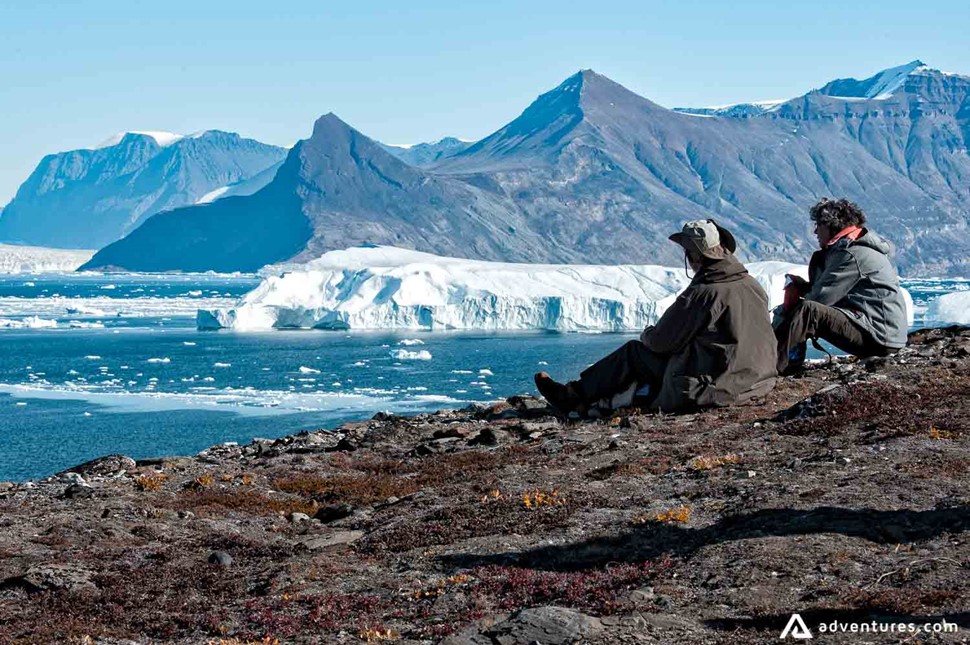 hikers resting near a shore in greenland