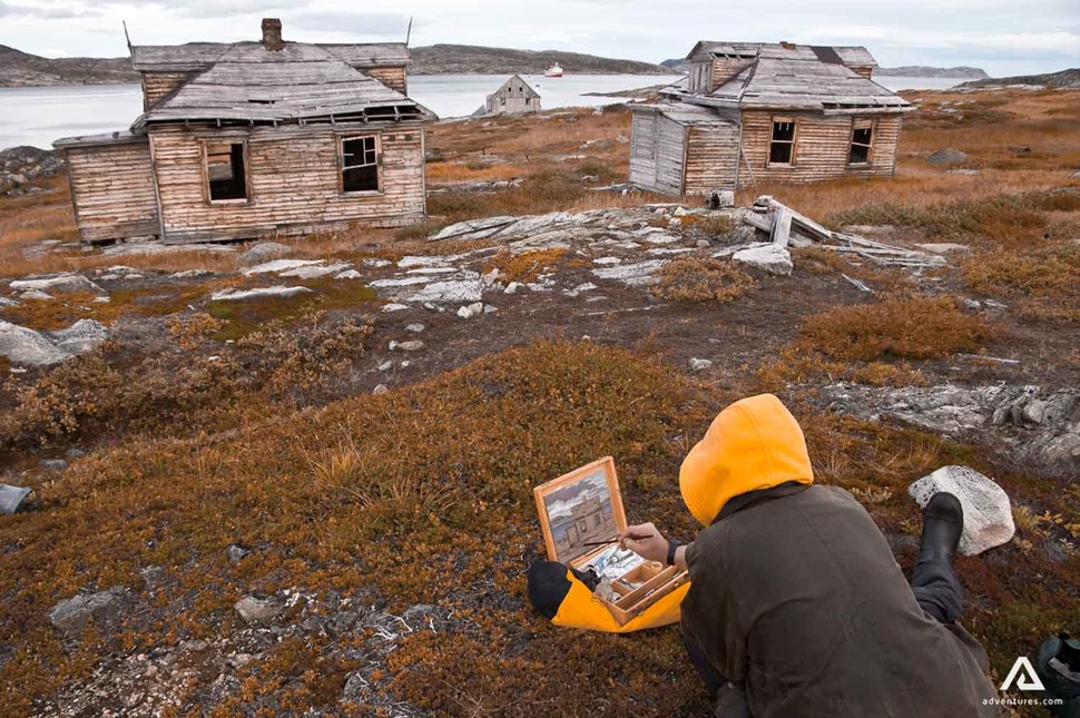 artist painting near wooden houses in canada