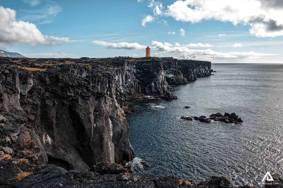 lighthouse near steep cliffs in iceland
