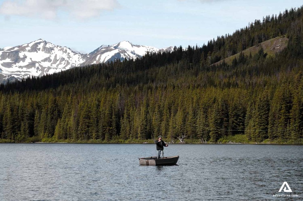 man fishing alone in a boat near forest