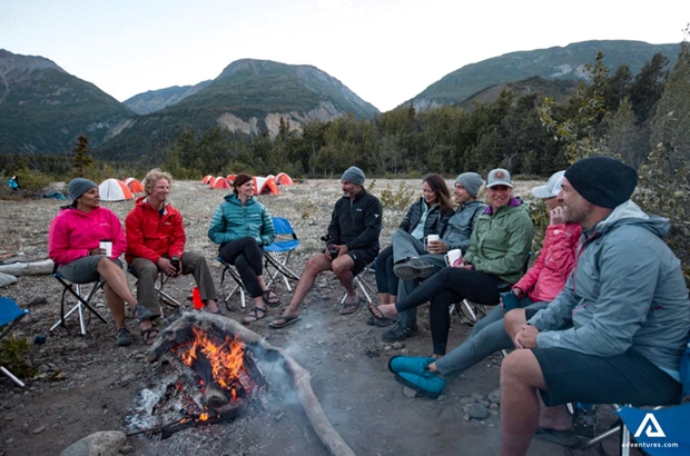 group camping and relaxing near a campfire
