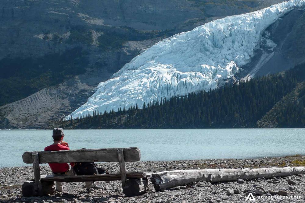 Man sits on the bench beside mountain lake