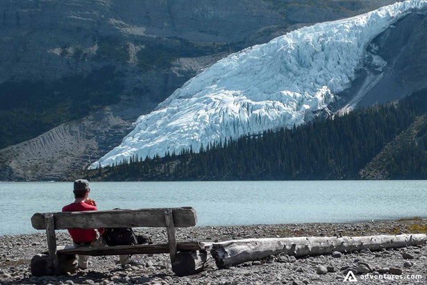 Man sits on bench beside lake