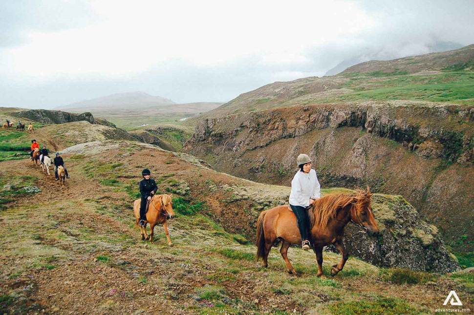 small group horseback riding near a canyon in iceland
