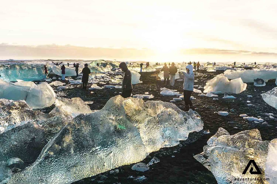 people walking around icebergs on diamond beach in iceland