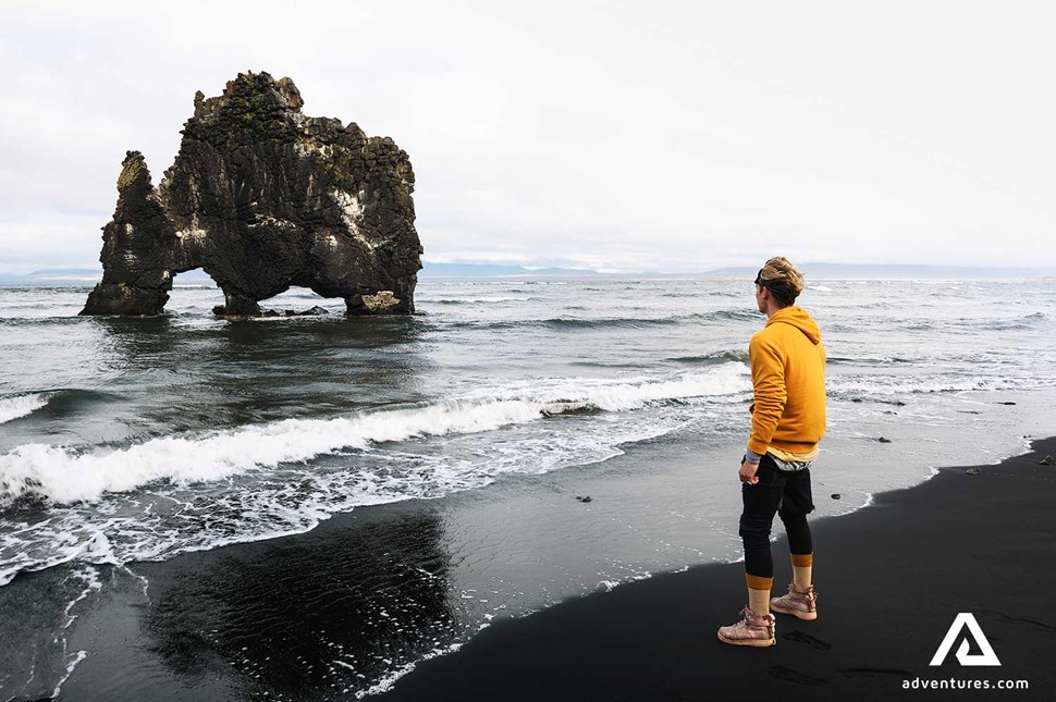 a man standing near hvitserkur rock formation in iceland