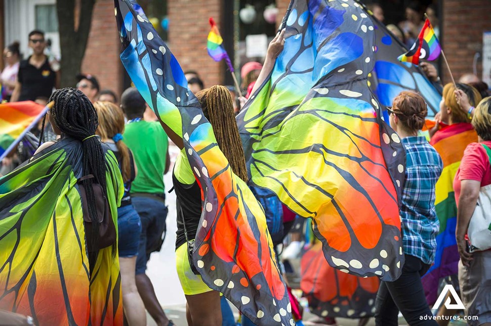 people dressed as rainbow coloured butterflies on a parade
