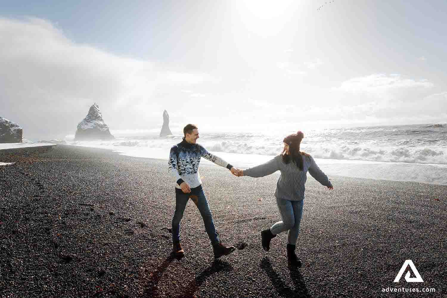happy couple running in reynisfjara black sand beach
