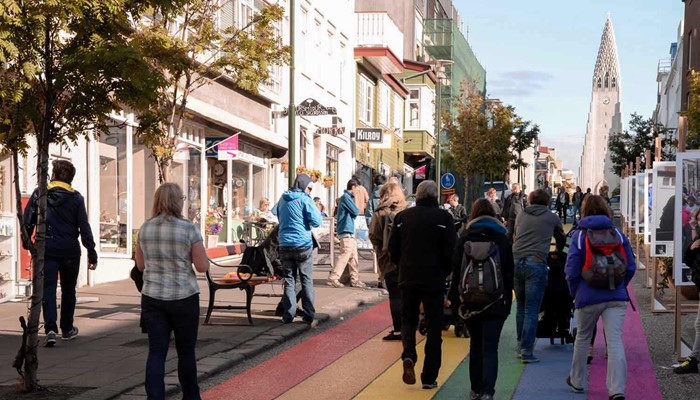 people walking down a rainbow painted road towards hallgrimskirkja