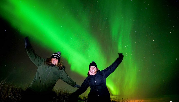 two women happy near northern lights in iceland