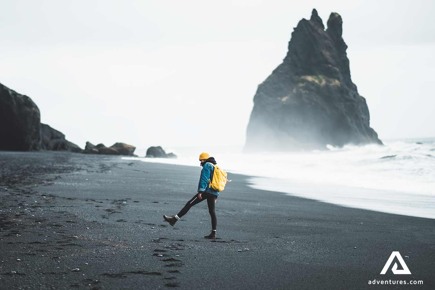 man walking around reynisfjara black sand beach