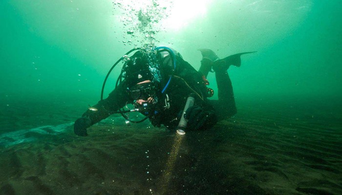 scuba diver with a flashlight in iceland