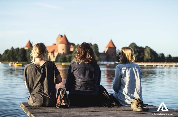 friends sitting on the side of galve lake in lithuania