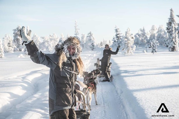 happy people dog sledding in finland