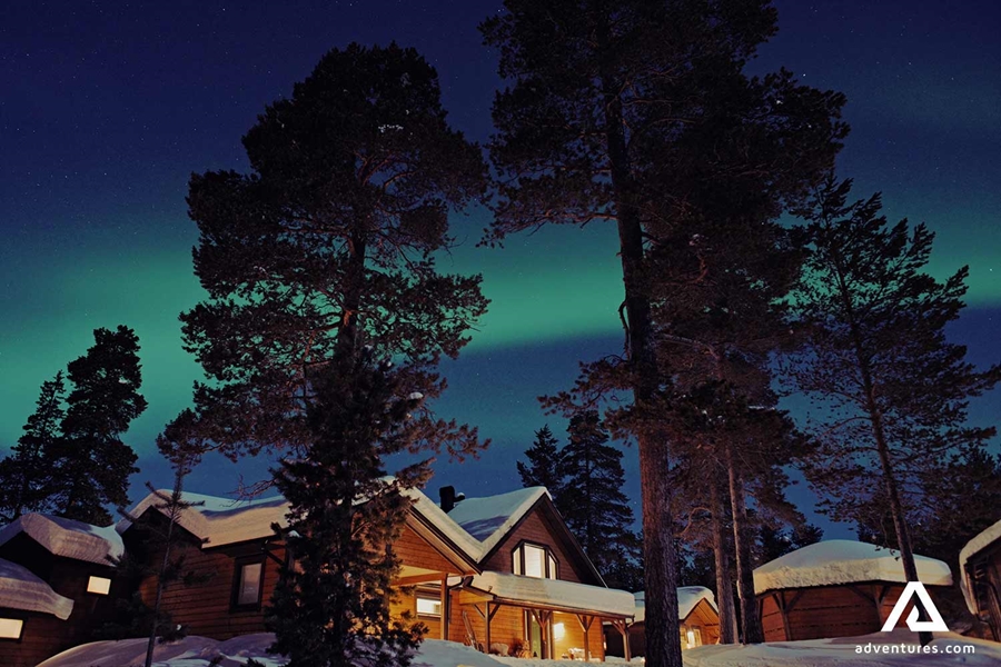 northern lights above forest cabins
