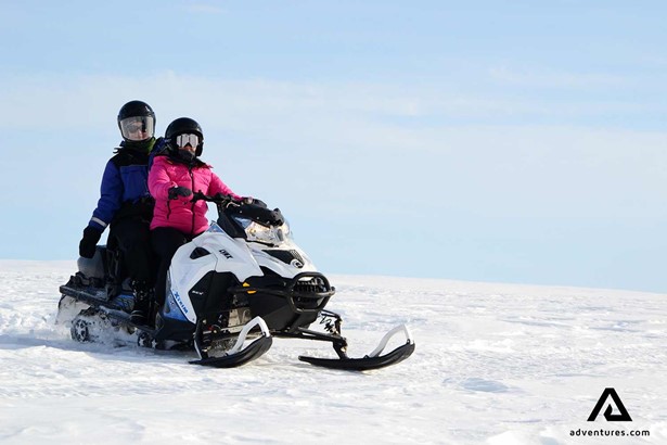 two people riding a snowmobile in sweden