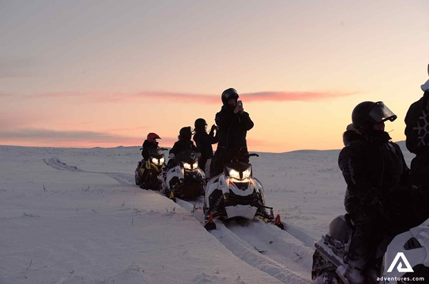 riding snowmobiles while sun is setting in sweden