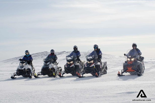 group of people snowmobiling in lapland