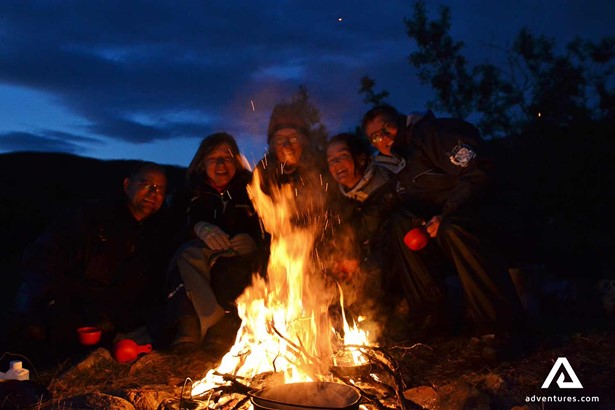 happy friends singing near a campfire in sweden at night