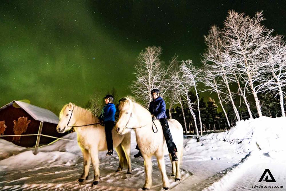 horse riders watching northern lights