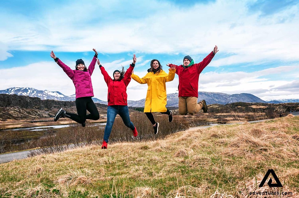 group of friends jumping in a field in iceland