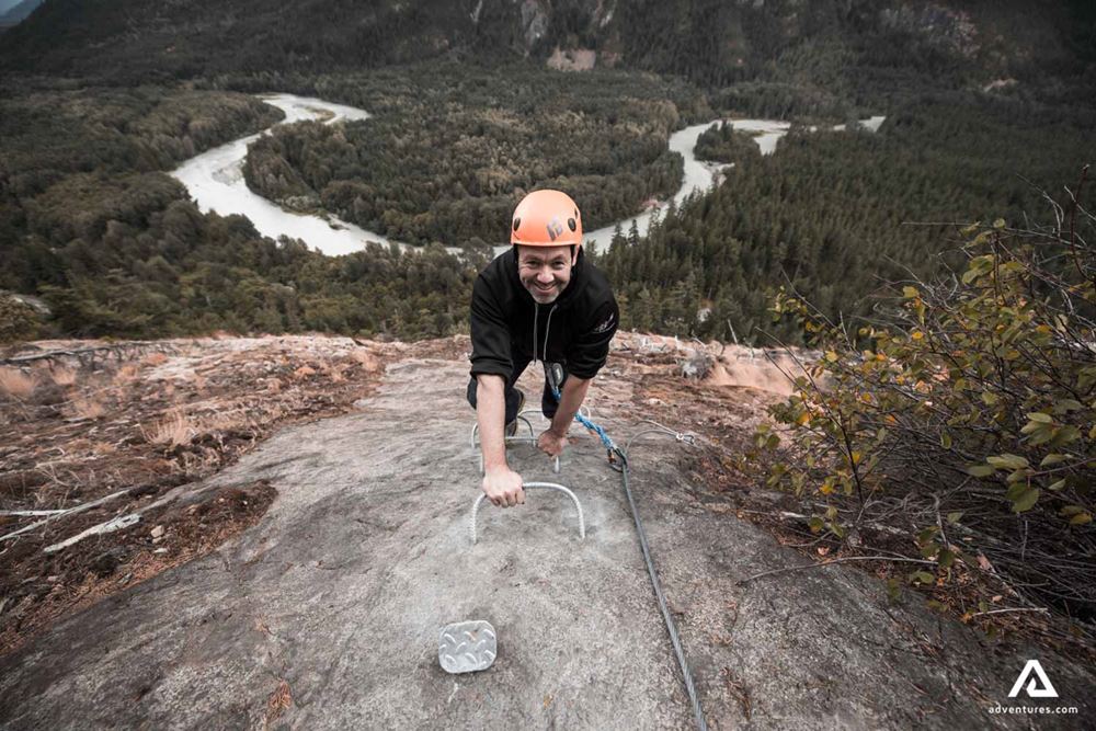Happy man climbing on high rock