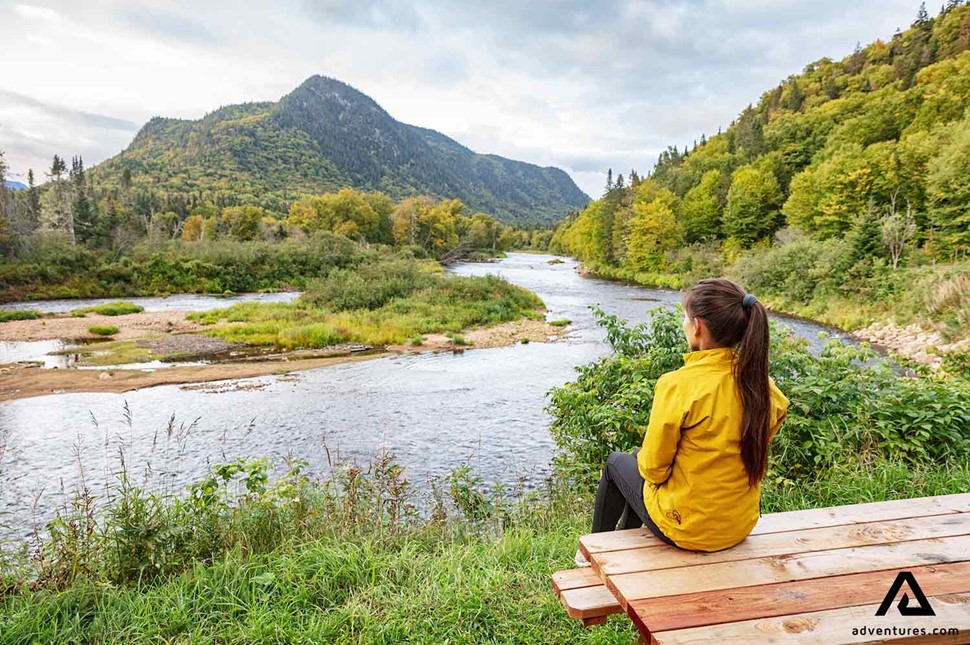 woman resting on a bench near a river in canada