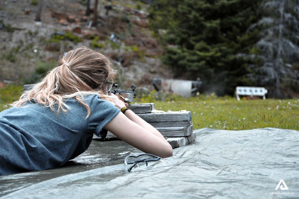 Girl lying down and shooting with a rifle