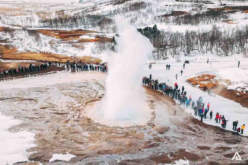 people near geysir eruption in winter 