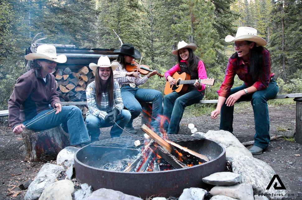 happy friends gathered around campfire and singing