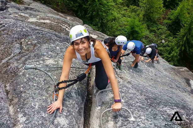 smiling woman rock climbing up a cliff