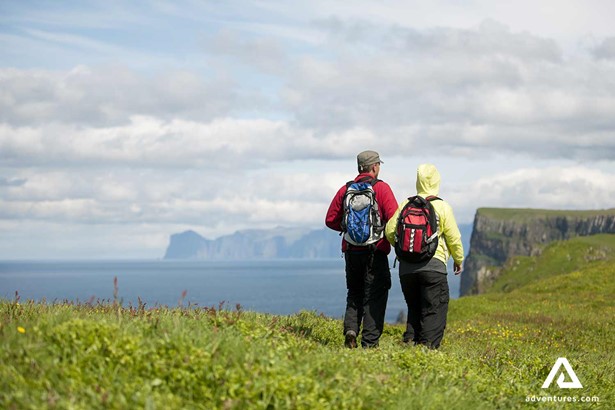 couple hiking near cliffs of mykines town area