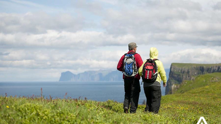 couple hiking near cliffs of mykines