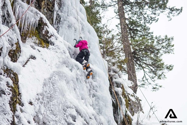 girl ice climbing a frozen waterfall in canada